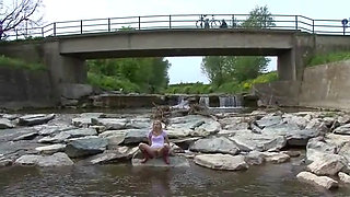 Blonde pissing outside in a river